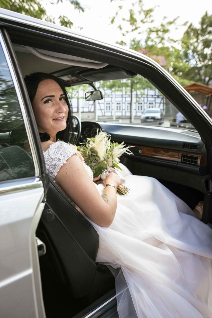 Braut schaut über ihre Schulter aus dem Hochzeitsauto