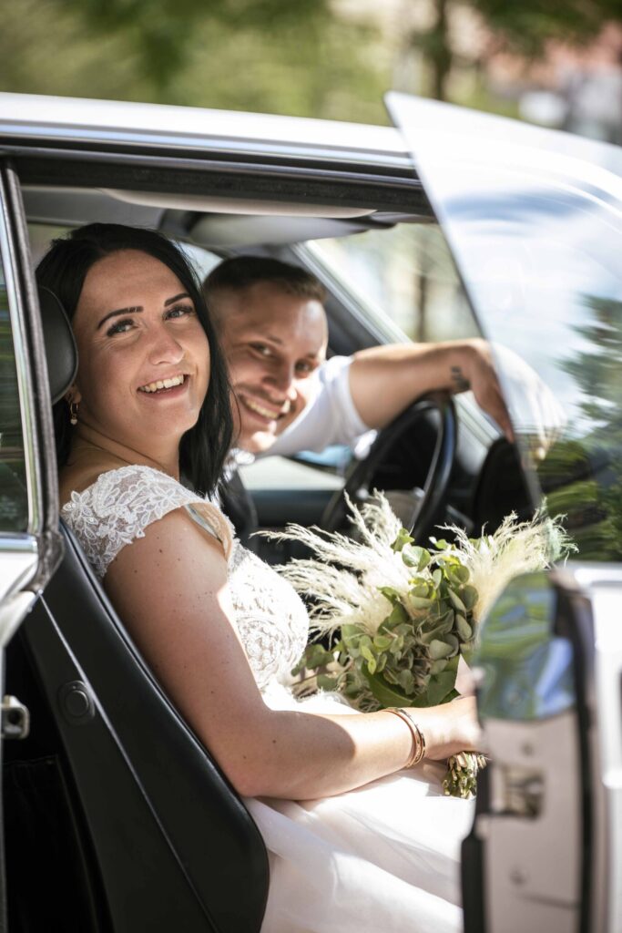 glückliches Hochzeitspaar sitzend im Hochzeitsauto