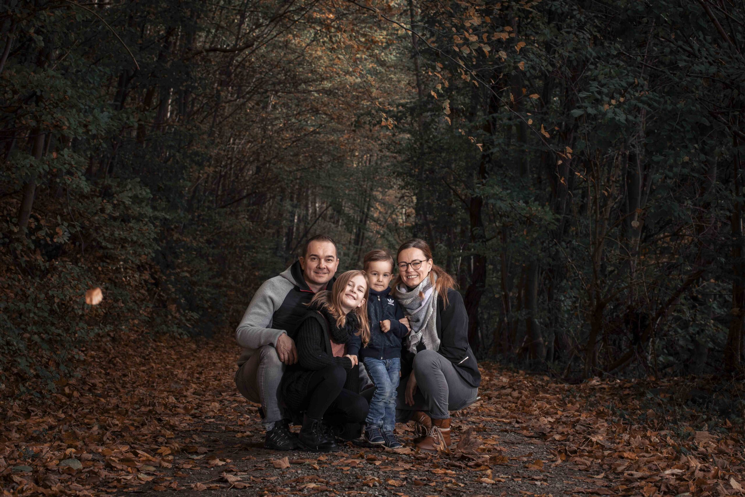 Familie mit zwei Kindern sitzt gemeinsam im herbstlichen Wald