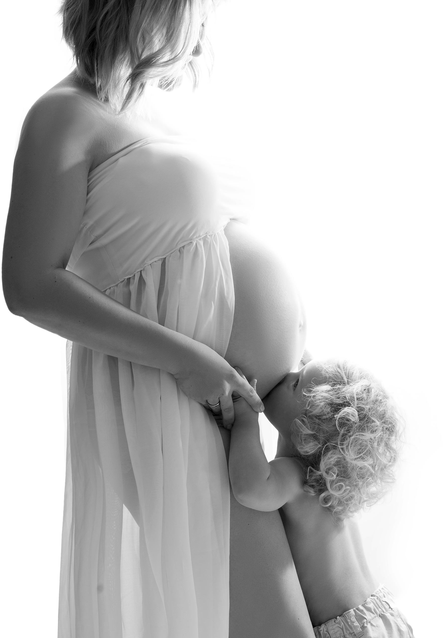 Tochter küsst den Babybauch ihrer Mutter
