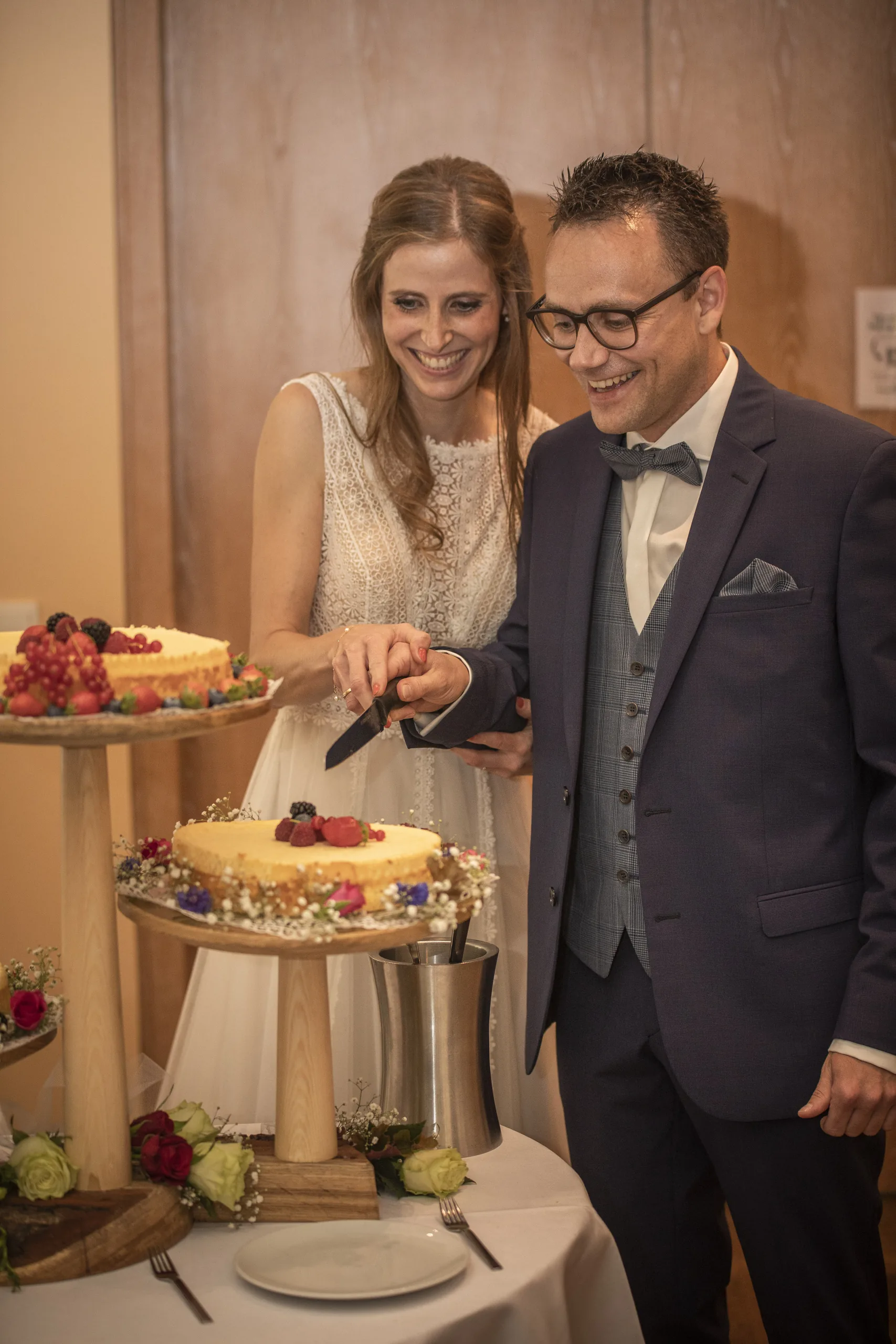 Brautpaar schneidet lachend die Hochzeitstorte auf der Burgruine Hardenberg in Nörten-Hardenberg an.