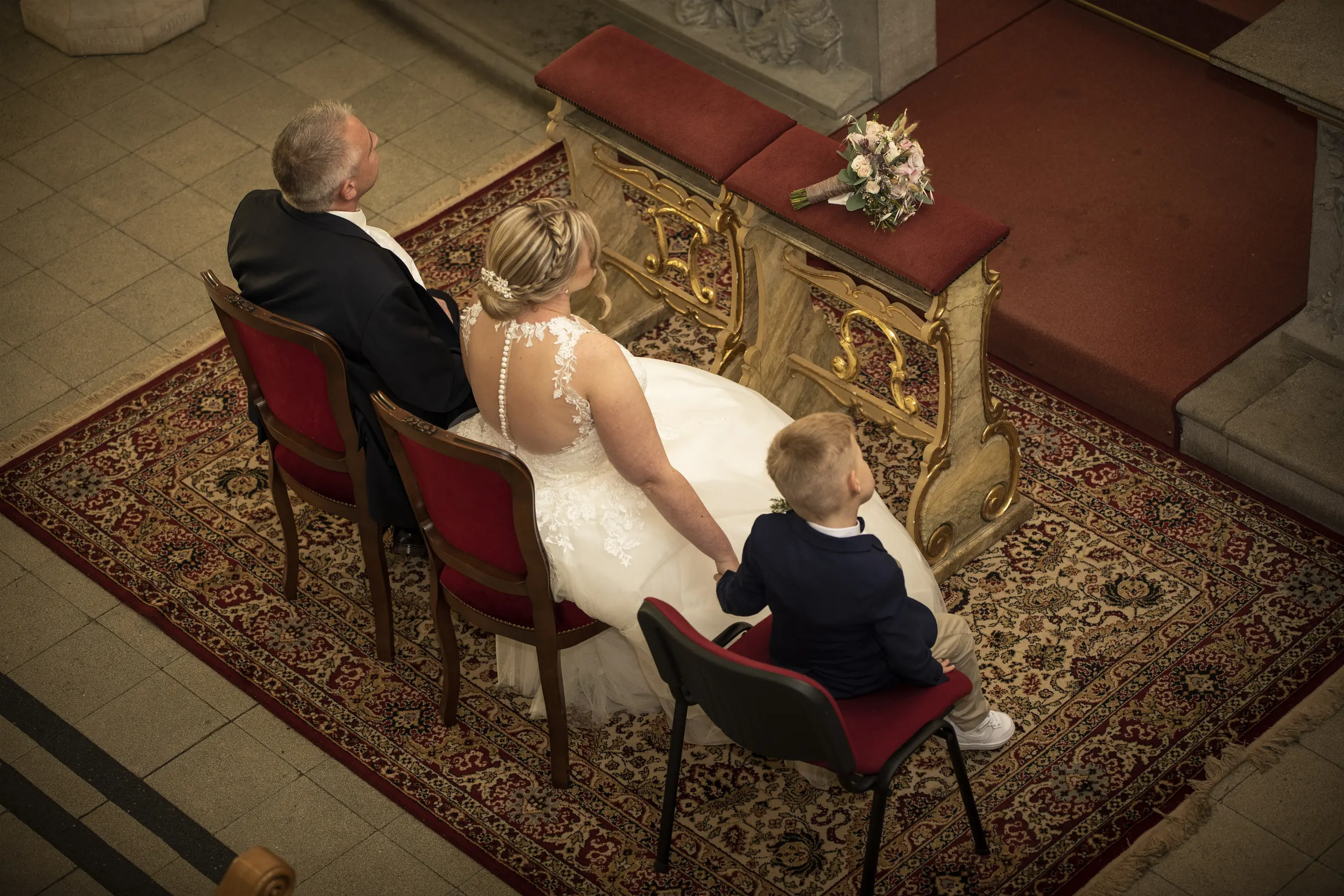 Brautpaar und Kind auf roten Stühlen von oben in der Pfarrkirche St. Gerhard in Heilbad Heiligenstadt.