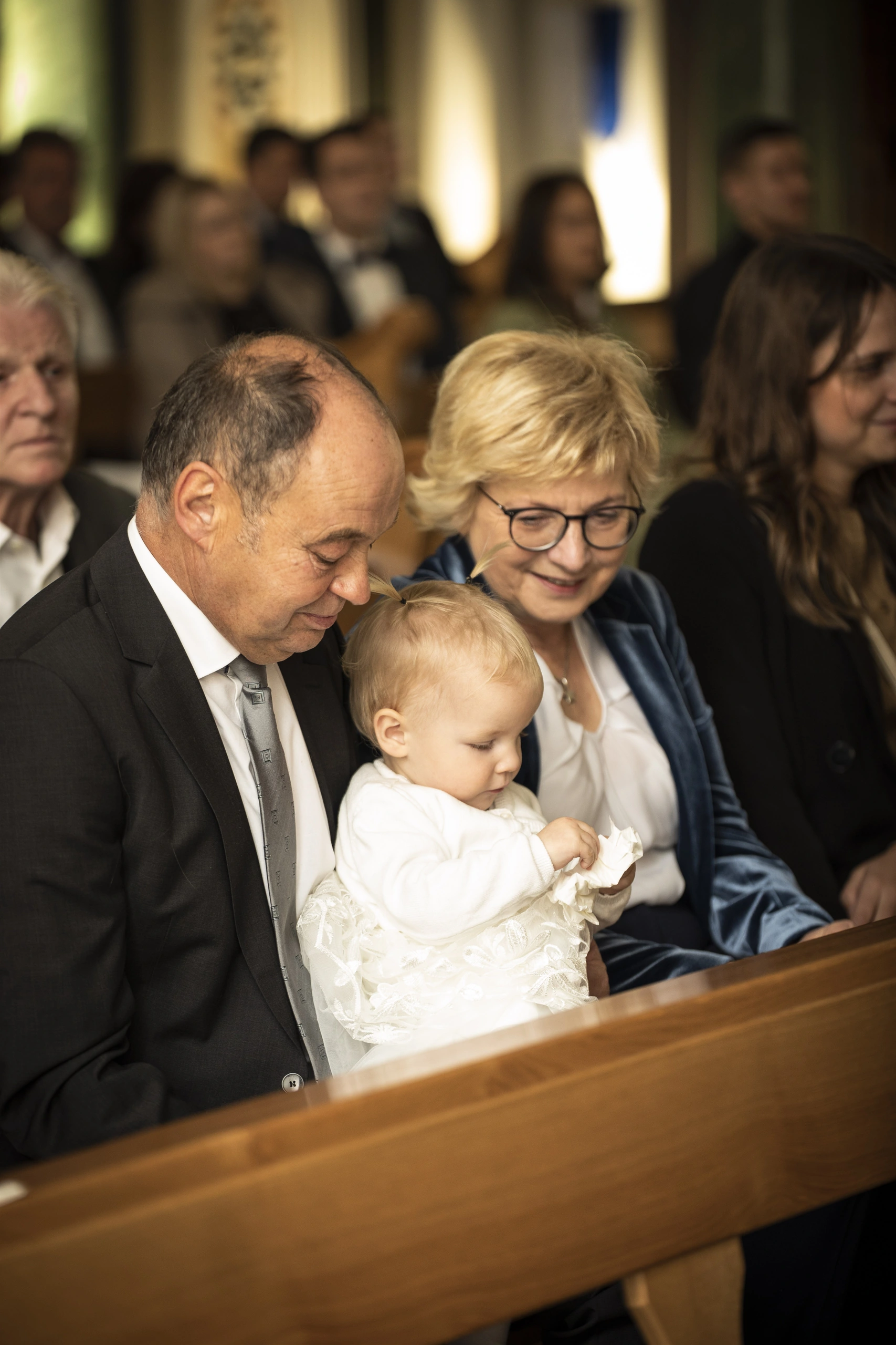 Hochzeitsgäste mit Kleinkind auf einer Kirchenbank in der Pfarrkirche St. Gerhard in Heilbad Heiligenstadt.