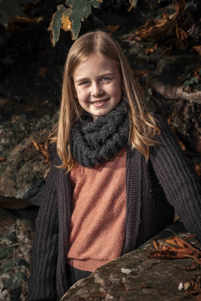 Mädchen mit dunklem Strickschal bei einem Kinderporträt im Wald.