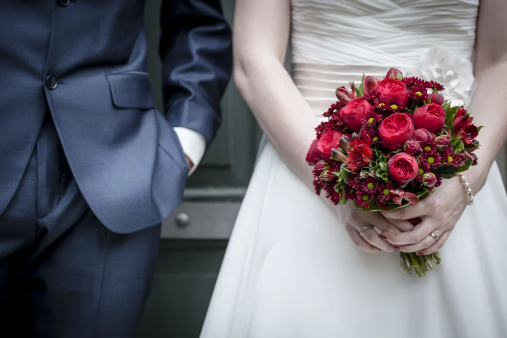 Timo und Franzi mit rotem Brautstrauß bei ihrer Hochzeit auf den Schillerwiesen